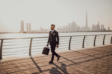 man walking on pavement while holding a bag